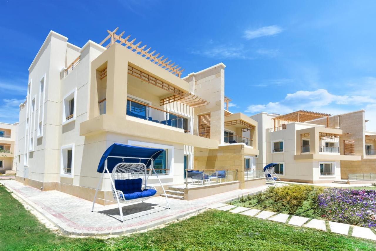 Tolip Resort El Galala Majestic Ajn Suchna Zewnętrze zdjęcie The photo displays a modern residential complex featuring two or more white buildings with a contemporary architectural design. Each building has balconies, large windows, and a sunshine-friendly layout that maximizes natural light. In the foreground