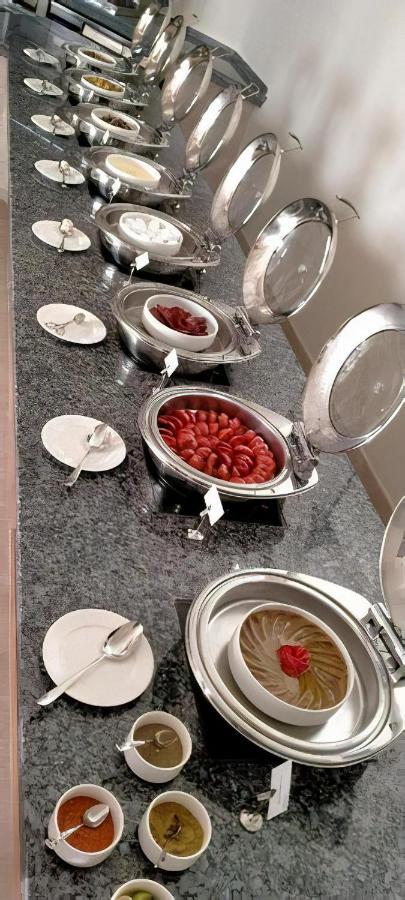 Tolip Resort El Galala Majestic Ajn Suchna Zewnętrze zdjęcie The photo shows a buffet setup featuring multiple metal serving trays on a dark granite countertop. One tray contains circular slices of food, possibly sausages or a similar dish, while another bowl holds what appears to be red food items, though it'