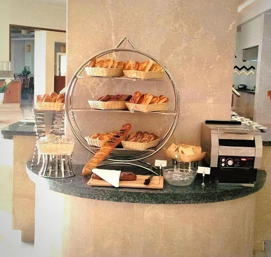 Tolip Resort El Galala Majestic Ajn Suchna Zewnętrze zdjęcie The photo shows a display of various types of bread and pastries arranged on a countertop. There are several baskets stacked on a circular stand, filled with different baked goods like croissants and rolls. A long baguette is placed horizontally on a