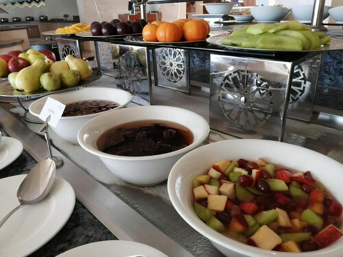 Tolip Resort El Galala Majestic Ajn Suchna Zewnętrze zdjęcie The photo shows a buffet-style arrangement of various fruits and fruit dishes. In the foreground, there are several bowls containing different types of fruit. One bowl has a fruit salad made with diced apples, green apples, and possibly other fruits.